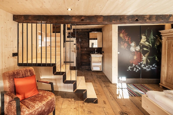A wooden interior with a staircase, a sofa, a cabinet, and a floral artwork. - Raneburg Historic Estate With Sauna (Matrei in Osttirol)