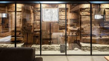 Ein rustikales Interieur mit Steinwand, Holzbalken und einem Fenster.