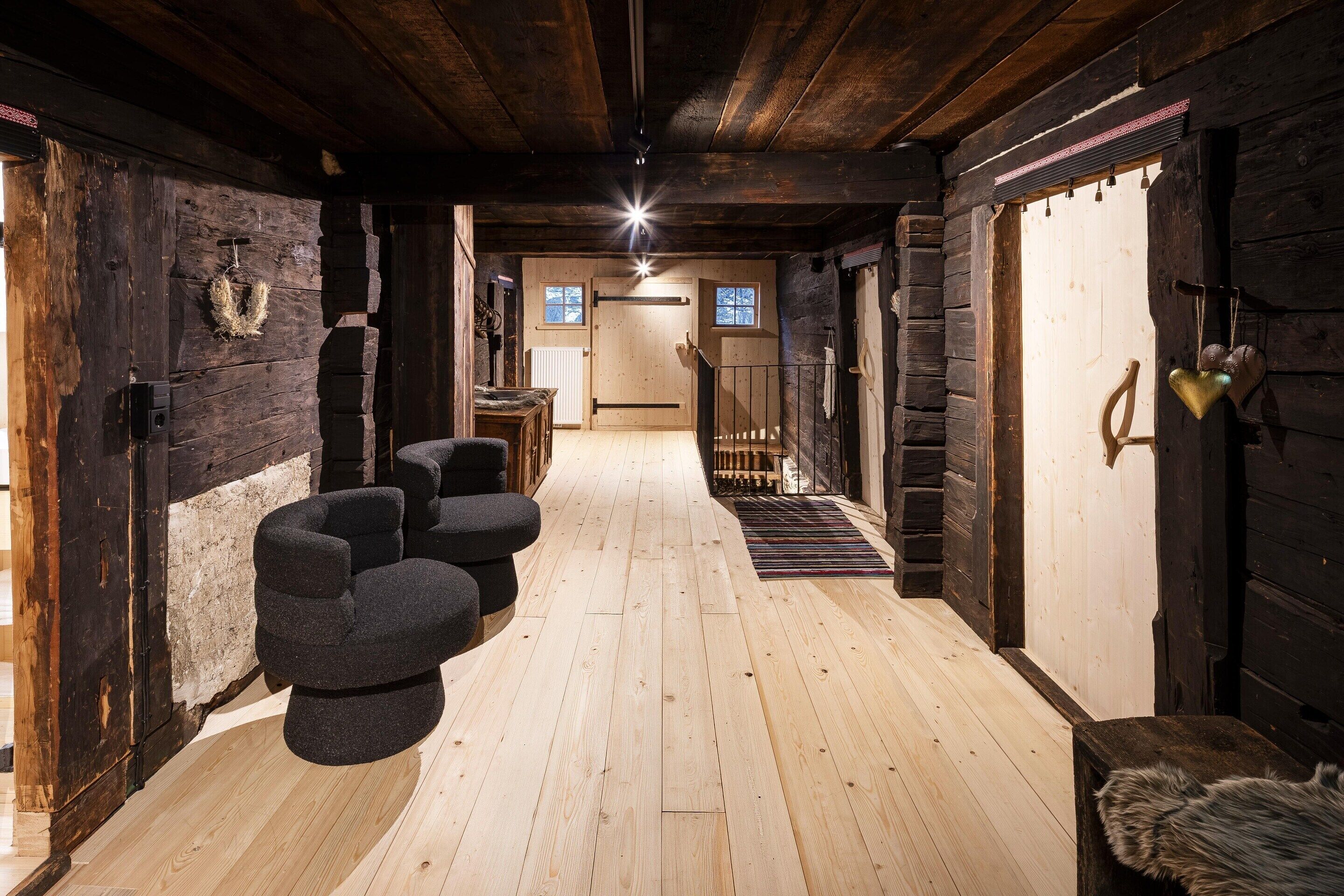 Un interior de madera con una zona de estar central y una escalera que lleva a una puerta.