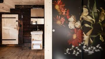 A wooden interior with a wooden door, a sink, and a mirror.