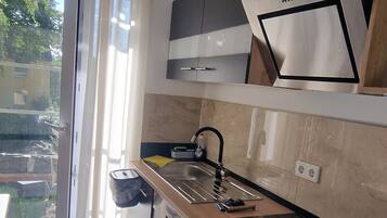 Una cocina moderna con horno empotrado, un lavamanos y una zona de comedor con una silla.
