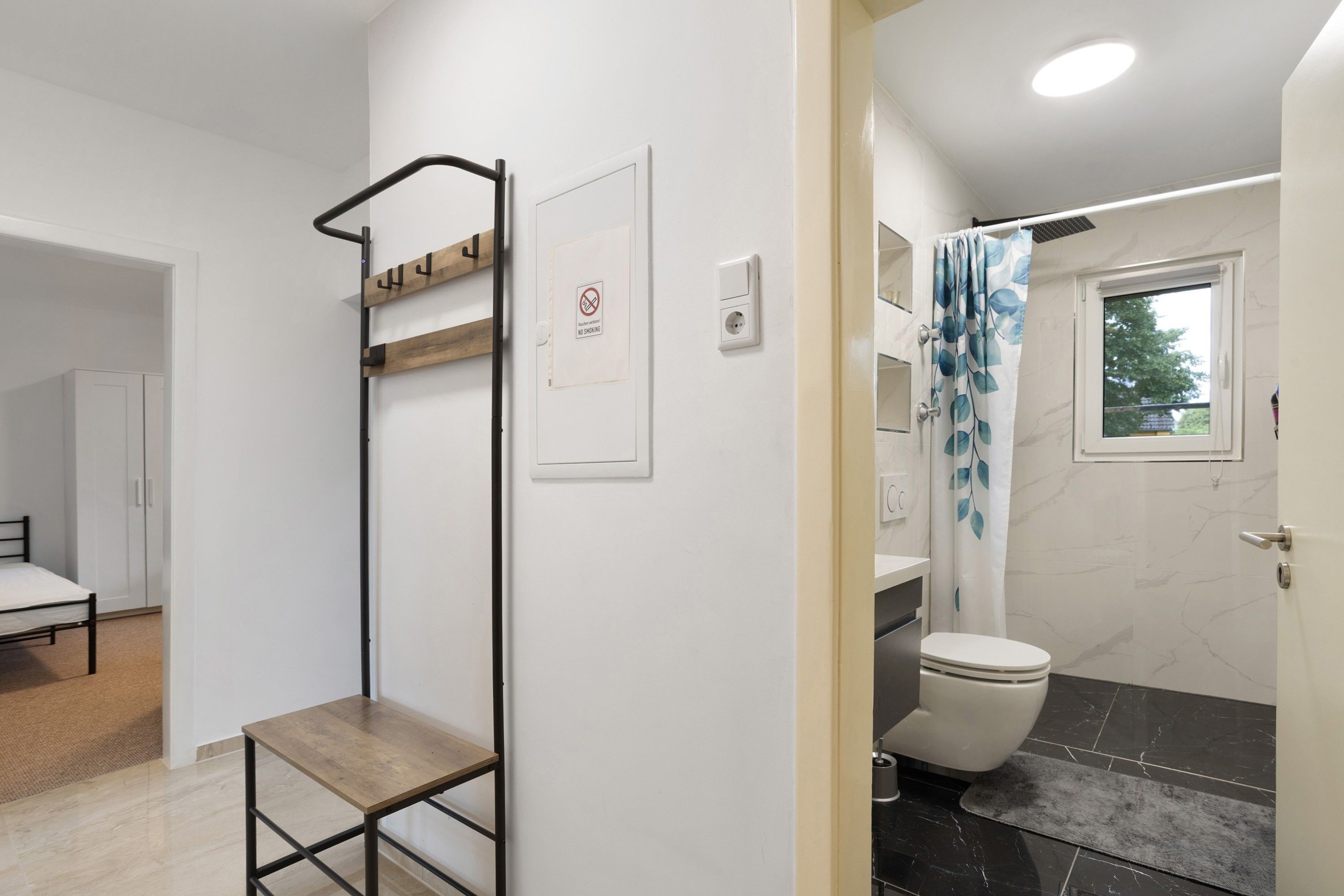 A bathroom with a shower, toilet, and a wooden shelf unit.