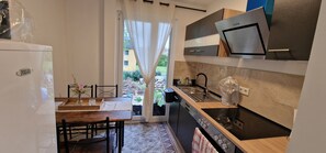 Une cuisine compacte équipée d’un four encastré, d’un évier et d’un coin repas avec une table et des chaises.