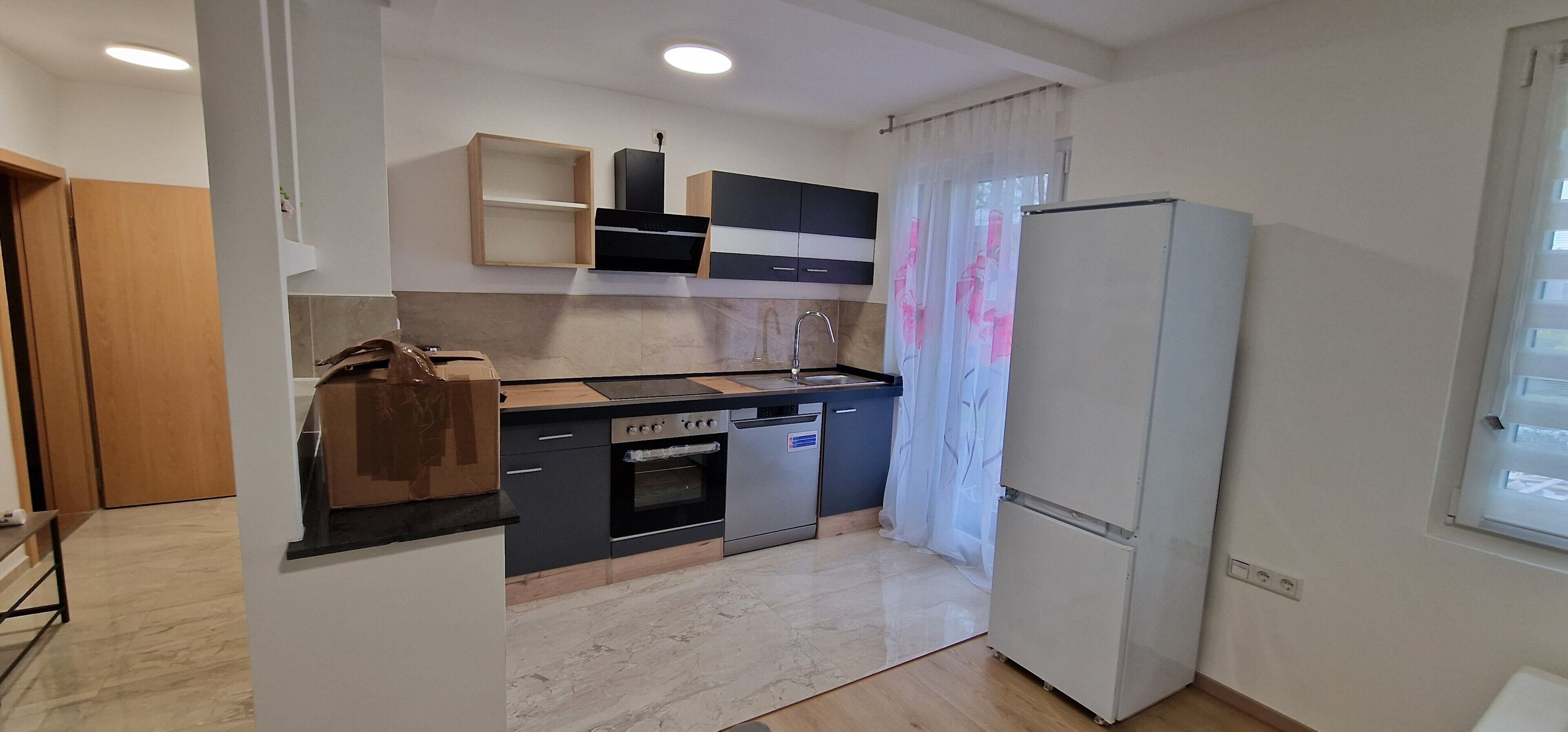 A compact kitchen with a refrigerator, oven, dishwasher, and a wooden countertop.