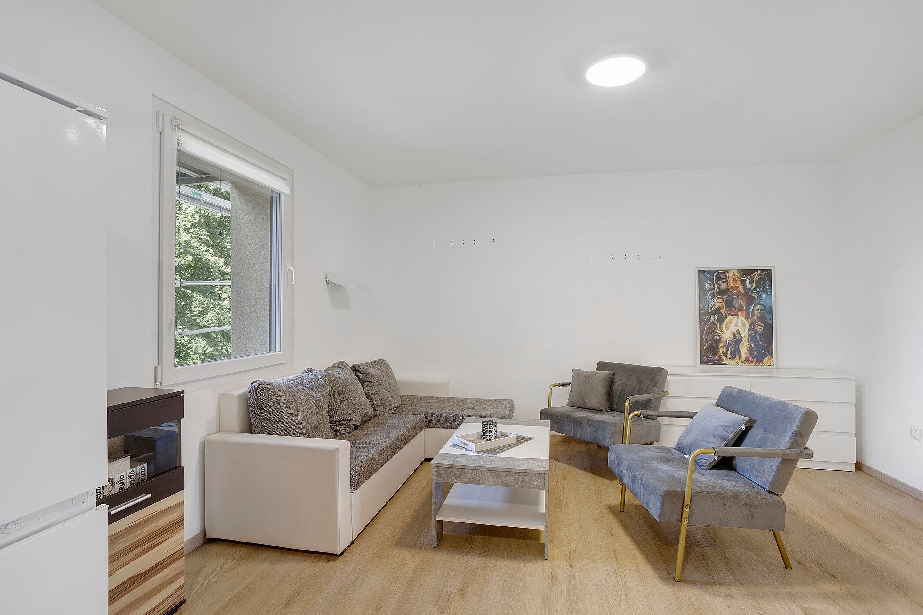 A modern living room with a sofa, armchairs, a coffee table, and a painting on the wall.