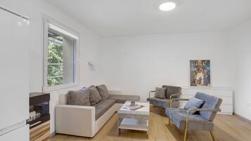 A modern living room with a sofa, armchairs, a coffee table, and a painting on the wall.
