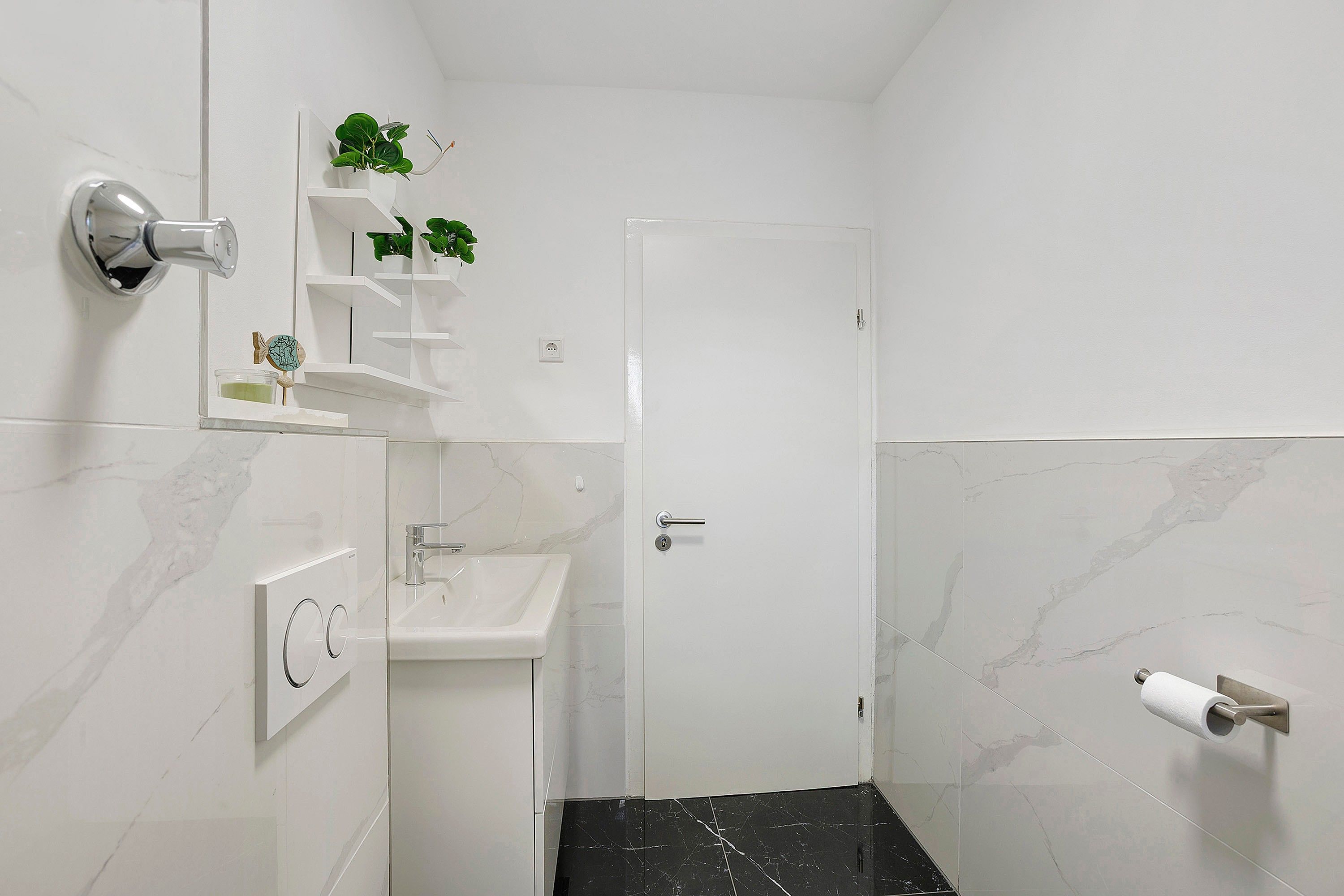Ein Badezimmer mit Waschbecken, Spiegel, Toilette, Duschbereich und einer Tür.