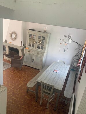 A room with a white cabinet, wicker chairs, a wooden table, and a fireplace. - Family villa by the sea (La Turballe)