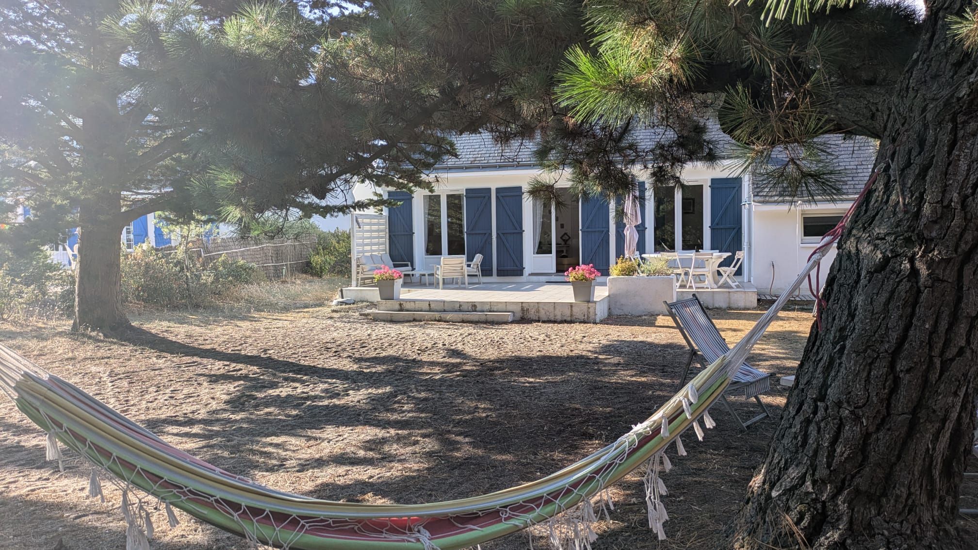 Una casa con porche cubierto, mobiliario exterior y una hamaca.