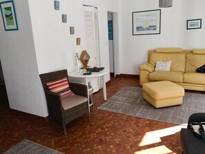 A living room with a wicker chair, a small white table, a yellow sofa, and a patterned rug. - Family villa by the sea (La Turballe)