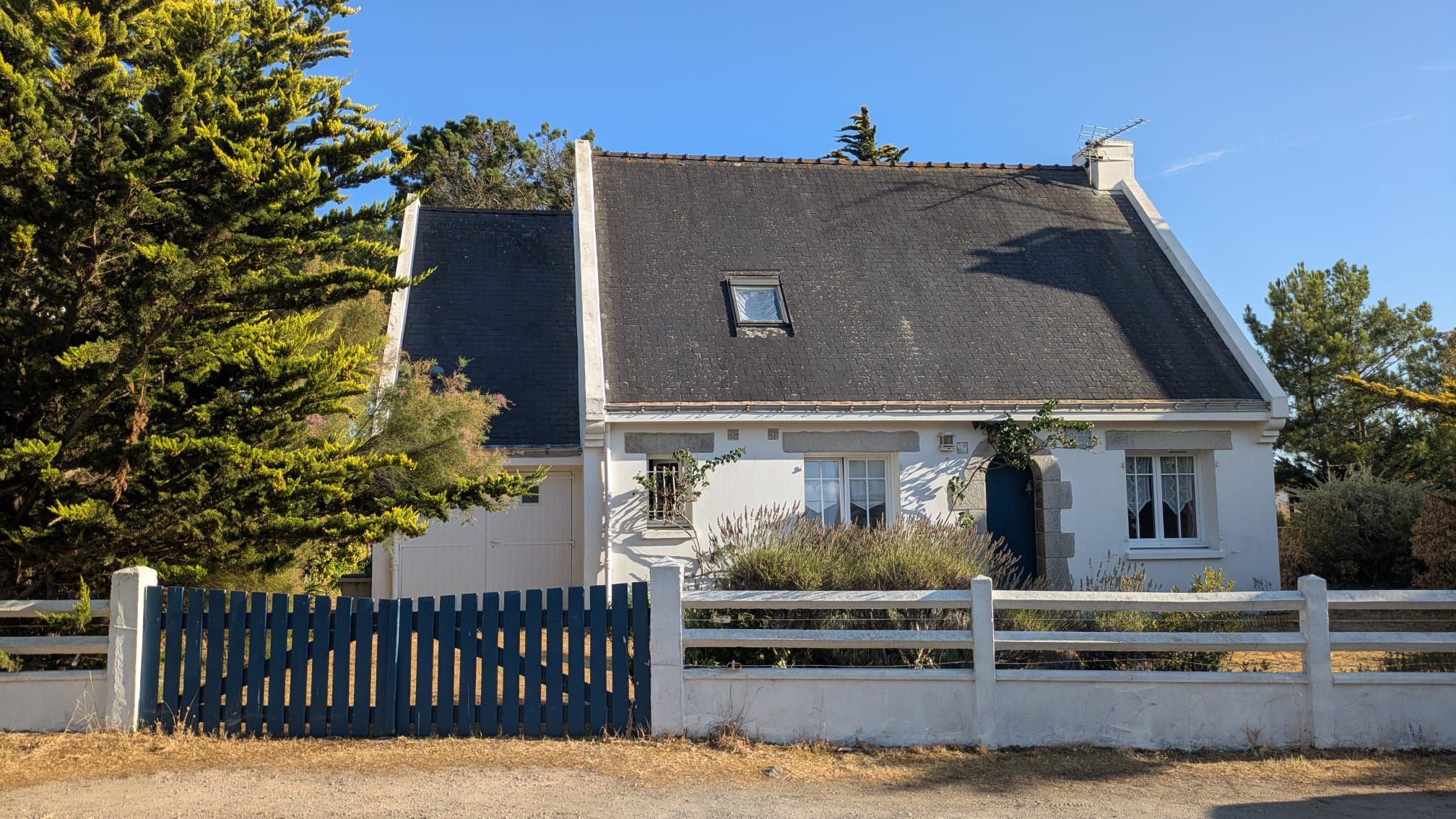 A two-story house with a dark roof, white exterior walls, and a small window.