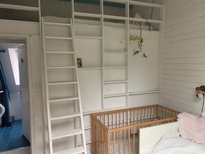 A room with a white crib, a white shelving unit, and a blue-tiled floor. - Family villa by the sea (La Turballe)