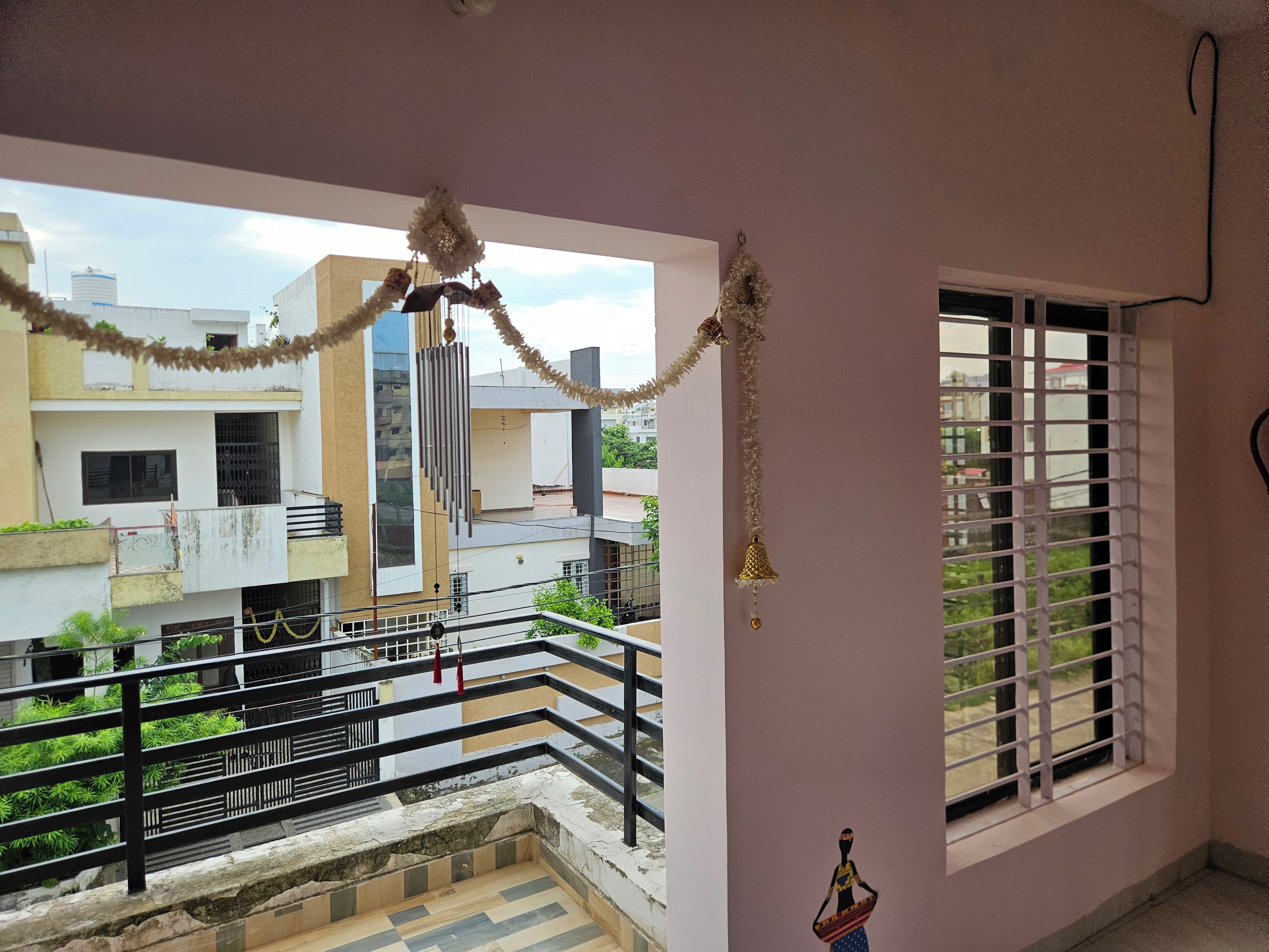 A balcony with a railing, a window with bars, and a view of neighboring buildings.
