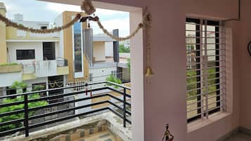 A balcony with a railing, a window with bars, and a view of neighboring buildings.