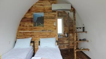 Una habitación con dos camas, paredes de madera, un cuadro, una escalera y una estantería con objetos.