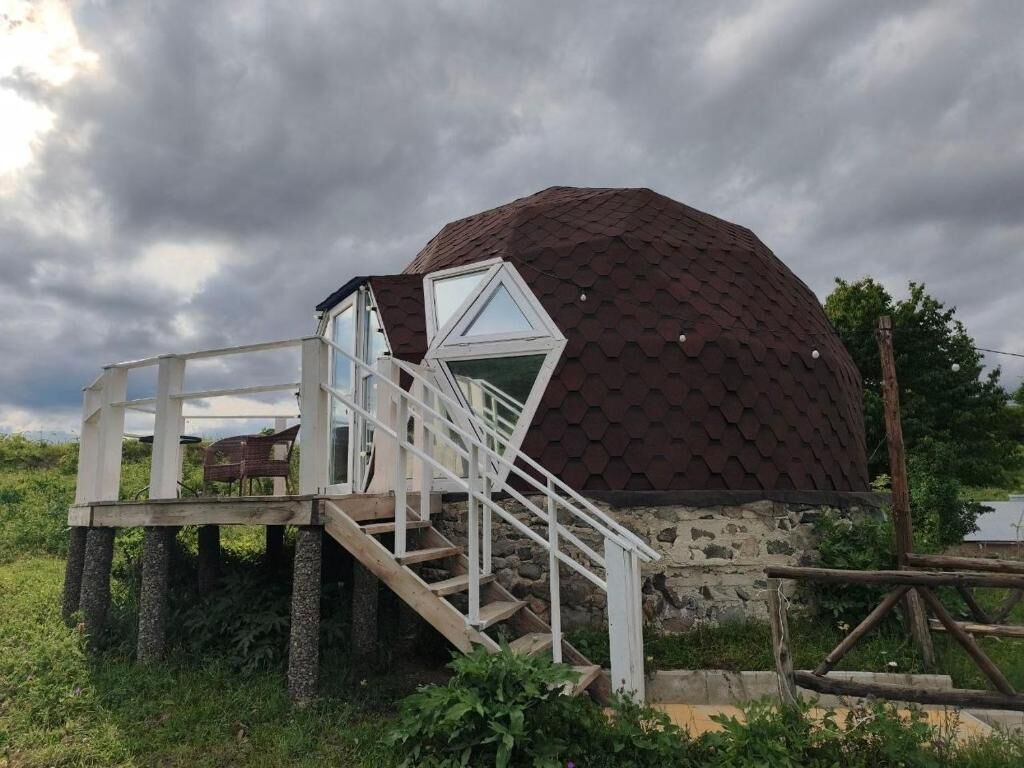 A geodesic dome structure with a staircase leading to a glass door entrance.