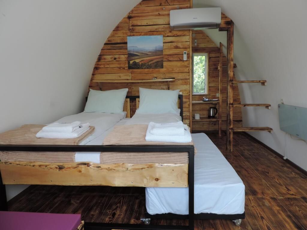 A wooden cabin-style room with a bed, a bench, and a small table.