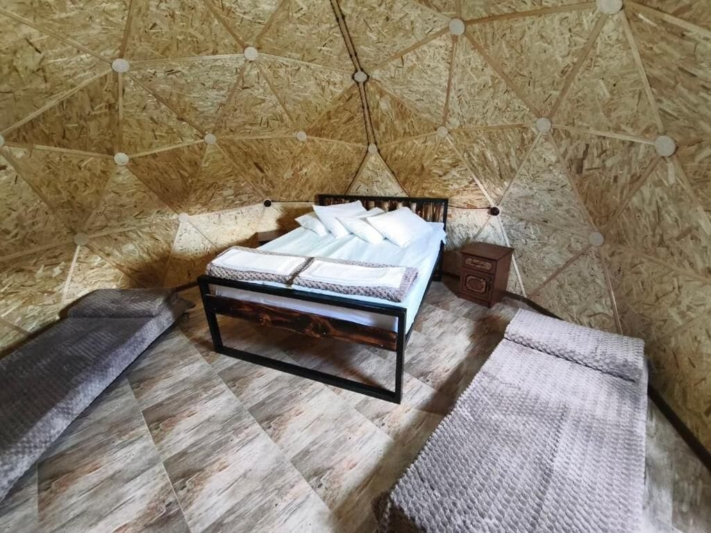 Une pièce comprenant un lit, une petite armoire en bois et un tapis à motifs.