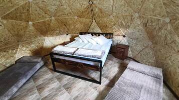 Une pièce comprenant un lit, une petite armoire en bois et un tapis à motifs.