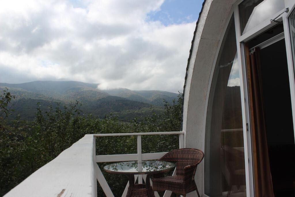 Uma varanda com mesa e cadeiras, com vista para uma paisagem montanhosa.
