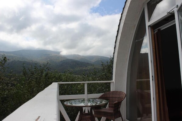 Un balcón con una mesa y sillas, con vista a un paisaje montañoso.