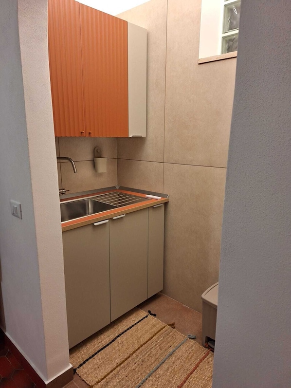 A compact kitchen with a sink, a countertop, and cabinets.