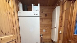 Ein kompakter Waschraum mit Waschmaschine und Trockner, Holzschränken und einem gemusterten Teppich.