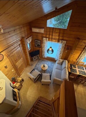 A wooden cabin interior with a sofa, chairs, a dining table, and a staircase. - Nietos B | Pet-Friendly Cabin with Private Sauna (Kuusamo)