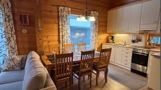 Ein Holzblockhaus-Interieur mit Essbereich, Küche und einer Couch.