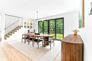 Ein modernes Interieur mit Treppe, Essbereich und großen Fenstern.