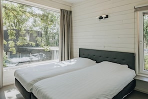 A bedroom with two beds, a window with curtains, and a wall-mounted light fixture. - Lodge in Schaijk with Garden Terrace (Schaijk)