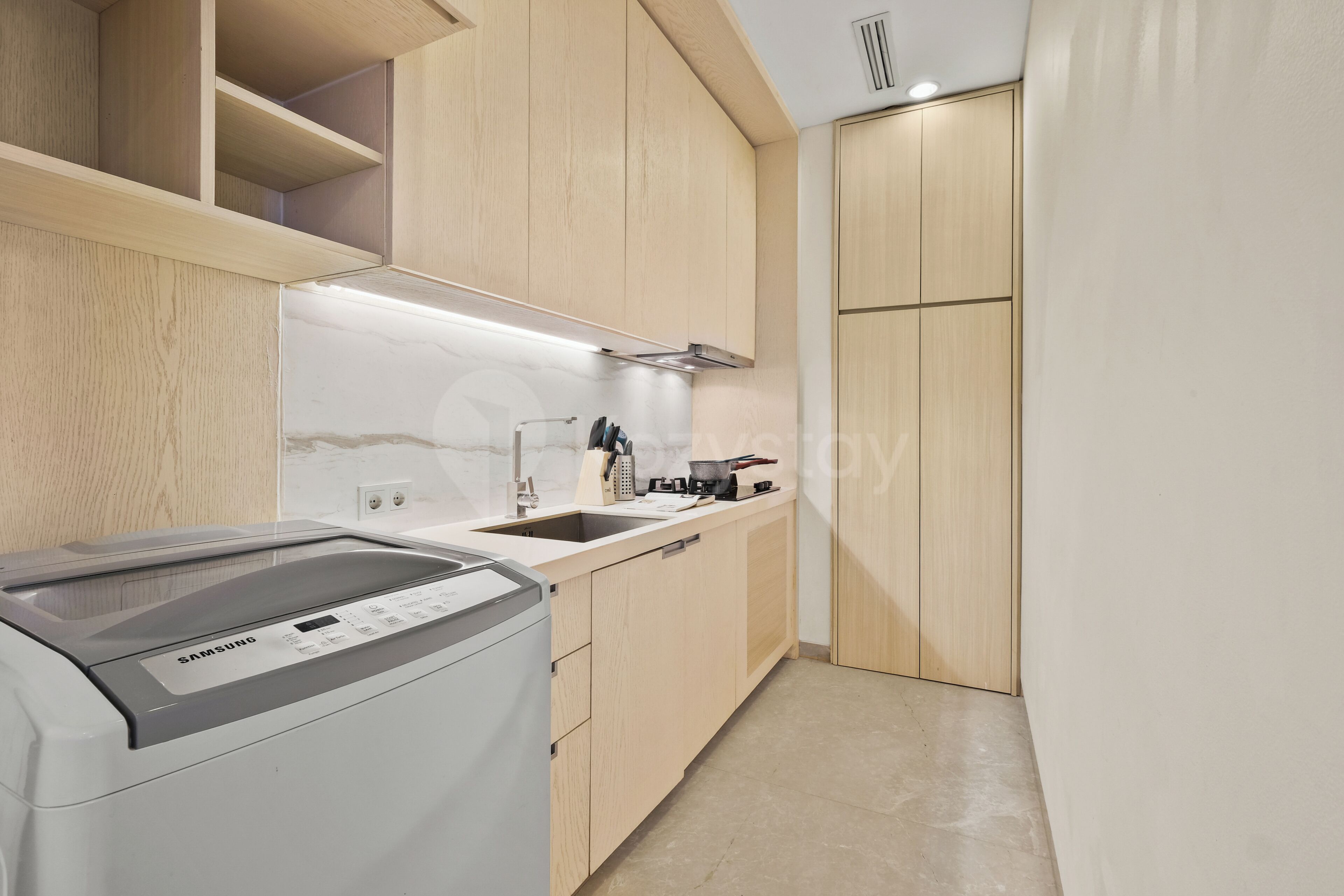 A modern kitchen with wooden cabinets, a built-in oven, and a stainless steel range hood.
