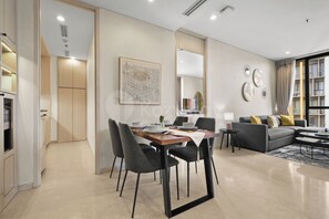 A modern living room with a dining area, a sofa set, and a large window. - Anera by Kozystay - Cilandak (South Jakarta)