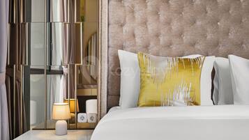 A hotel room with a bed, a nightstand with a lamp, and a mirror.