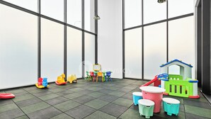 A children's play area with a green playhouse, colorful chairs, and a small table. - Anera by Kozystay - Cilandak (South Jakarta)