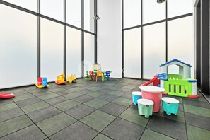 A children's play area with a green playhouse, colorful chairs, and a small table. - Anera by Kozystay - Cilandak (South Jakarta)