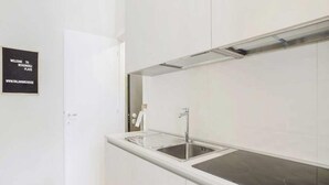 Eine moderne Küche mit einer Edelstahl-Spüle, einer weißen Arbeitsplatte und einer schwarzen Spritzschutzwand.