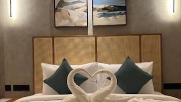A hotel room with a bed, two wall-mounted light fixtures, and two framed pictures on the wall.