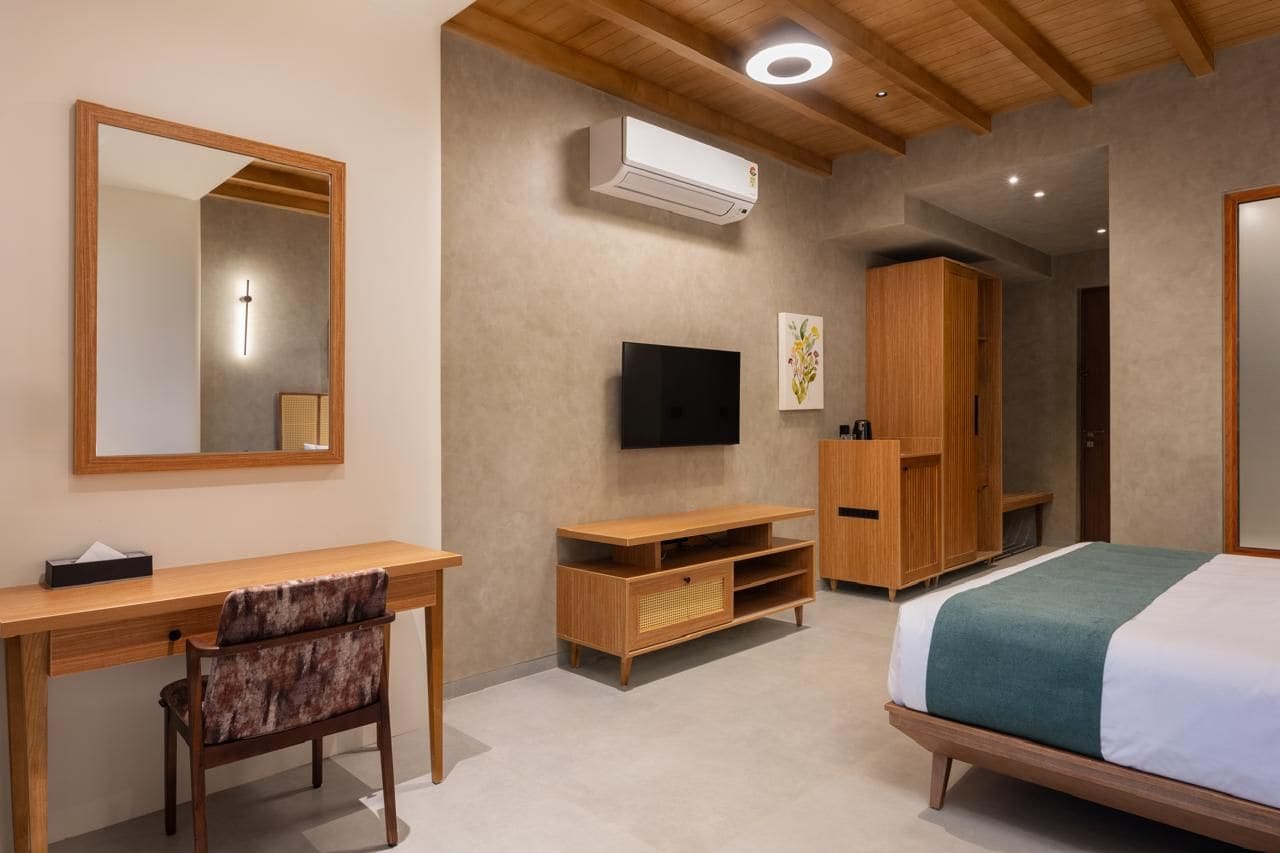 A bedroom with a bed, a desk, a chair, a TV, and a wardrobe.