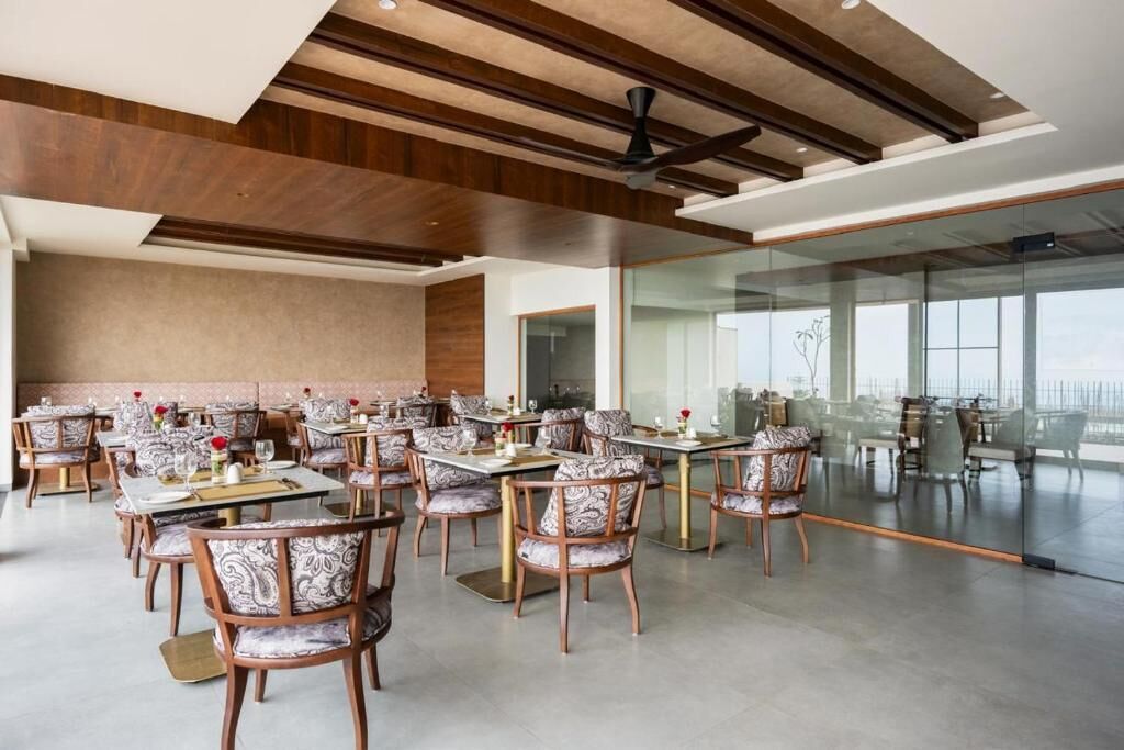 Un comedor amplio con múltiples mesas y sillas, un diseño de techo moderno y ventanas grandes que ofrecen vistas.