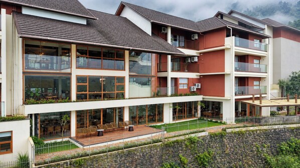 A multi-story residential building with balconies, large windows, and a covered outdoor seating area. - Olive Woods (Devikolam)