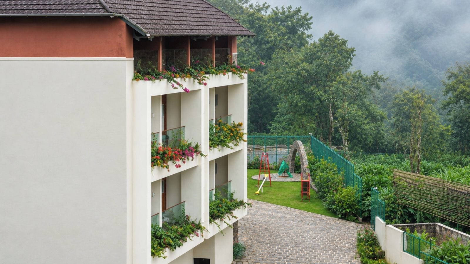 A multi-story building with balconies adorned with plants, a playground, and a stone pathway leading to a green area.