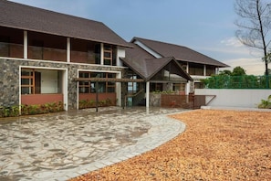 A modern building with a stone facade, large windows, and a covered entrance area.