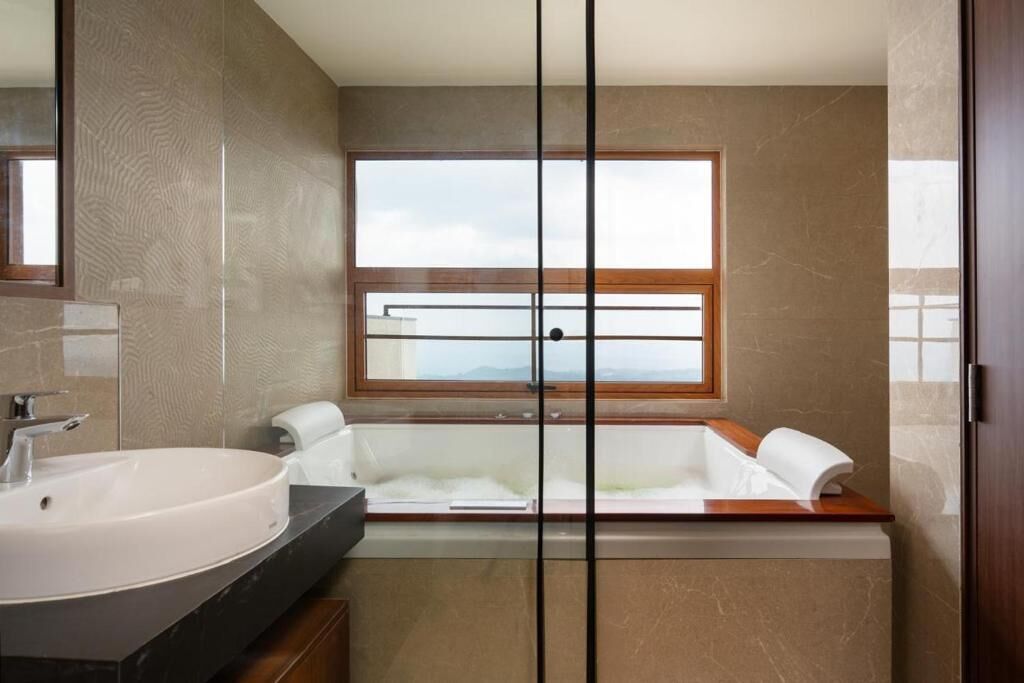 Un baño moderno con un lavamanos grande, una bañera y una ventana con vistas.