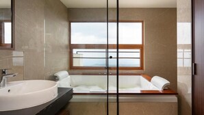 A modern bathroom with a large sink, a bathtub, and a window offering a view. - Olive Woods (CHINNAKANAL)