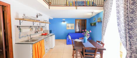 A kitchen with a dining area, a balcony, and a blue wall.