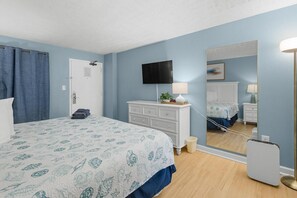 Ein Schlafzimmer mit Bett, Kommode, Fernseher, Spiegel und Nachttischlampe.