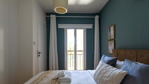 A bedroom with a bed, a window with curtains, a wall-mounted light fixture, and a door. - Veta 31 . 1-BR Apt. & Balcony in Larnaca (Larnaca)