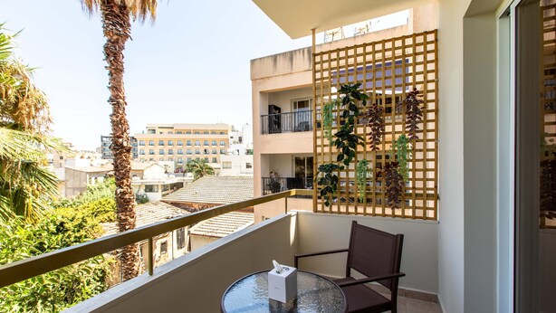 A balcony with a glass table, a chair, and a wooden lattice with plants. - Veta 31 . 1-BR Apt. & Balcony in Larnaca (Larnaca)