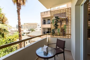 A balcony with a glass table, a chair, and a wooden lattice with plants. - Veta 31 . 1-BR Apt. & Balcony in Larnaca (Larnaca)